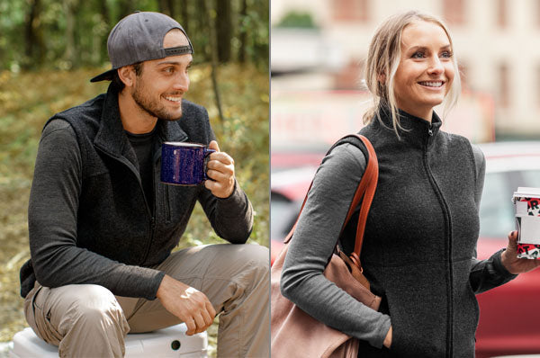 A man and a woman both wear dark gray zip-up vests; the man sits outdoors holding a mug, while the woman stands in an urban setting, smiling and holding a coffee cup.