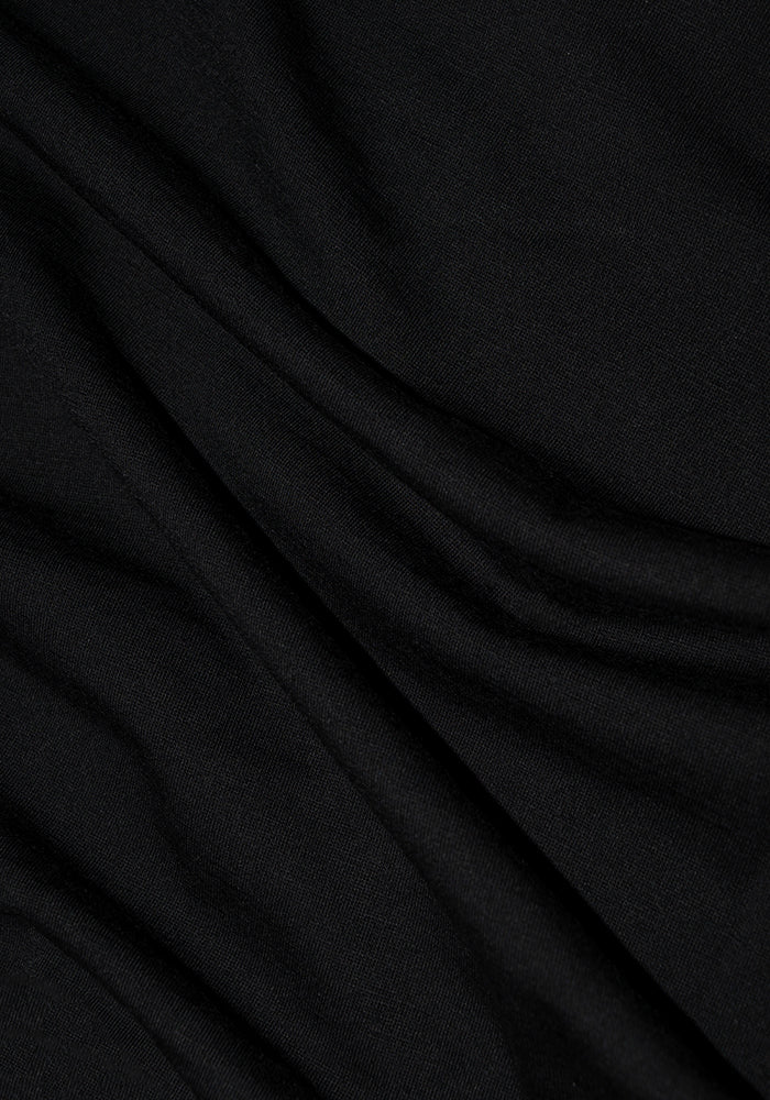 The Mia V Neck - Black by Woolx, made of black merino wool, features soft folds that create gentle waves on its surface, offering a smooth and slightly glossy texture for ultimate comfort.
