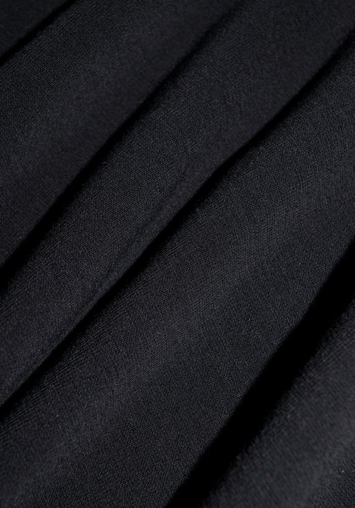 Close-up of the Woolx Hayden Bra in black, made from soft merino wool fabric with gentle folds and visible lines, highlighting its smooth texture and elegant shadows.