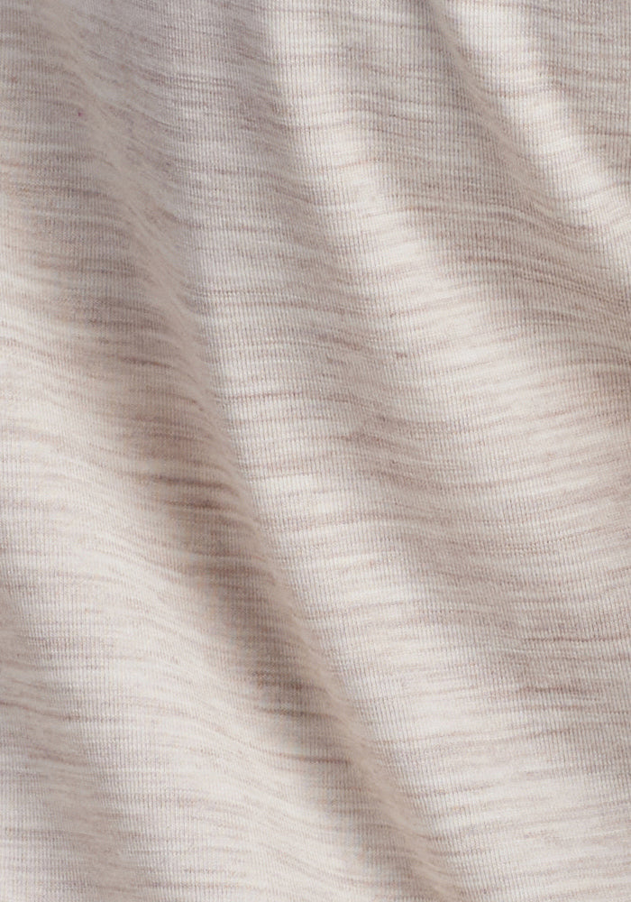 A close-up of Woolx's Mia V Neck in Cream Heather, featuring light beige Merino wool with a subtle stripe pattern. The soft, textured material forms gentle waves and folds, providing natural shadows and highlights for an odor-free cozy travel tee experience.