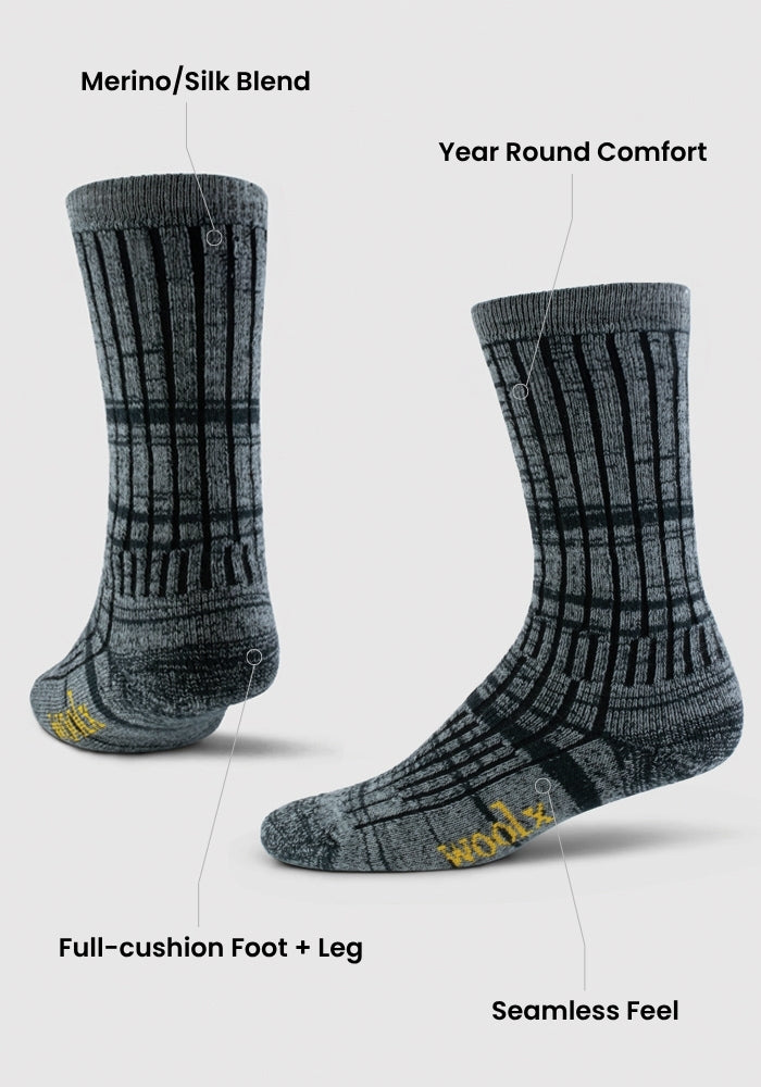 Two steel blue patterned Woolx Mens Joey Mid Calf Socks stand upright on a white background. Labels showcase a Merino/Silk blend, year-round comfort, full-cushion foot and leg, and a seamless feel for ultimate coziness.