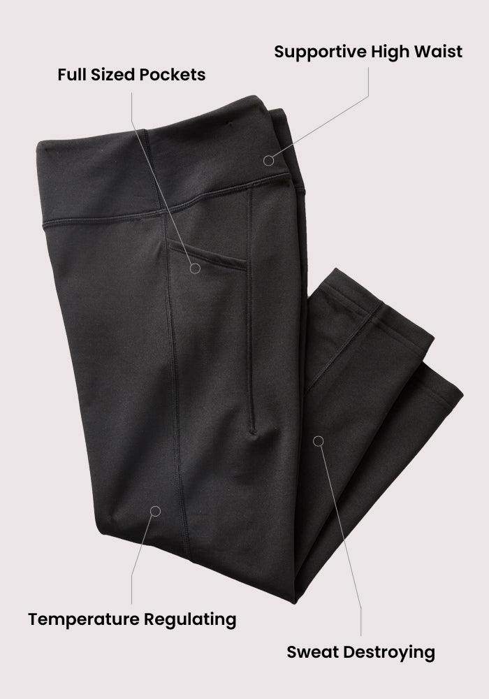 The Woolx Merino Flex® McKenna Tall - Black leggings are folded neatly, with labels showing full-sized pockets, a supportive high waist, temperature regulation, and sweat control. The light gray background highlights these versatile merino wool leggings.