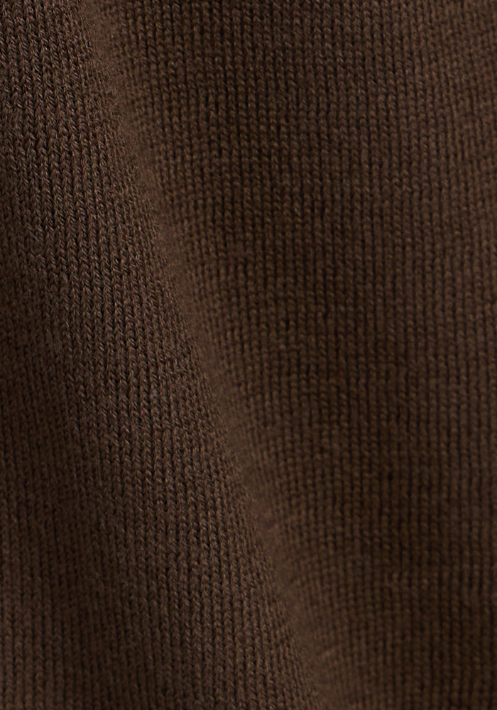 Close-up of the Woolx Macie Sweater in Bracken shows its brown knitted fabric with a textured pattern, visible stitches, and a subtle diagonal crease for added coziness.