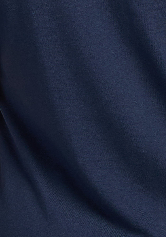 A close-up image of smooth, deep navy fabric with soft folds and subtle shadows, highlighting the luxurious texture of the Woolx Marilyn Flowy Midi Skirt.