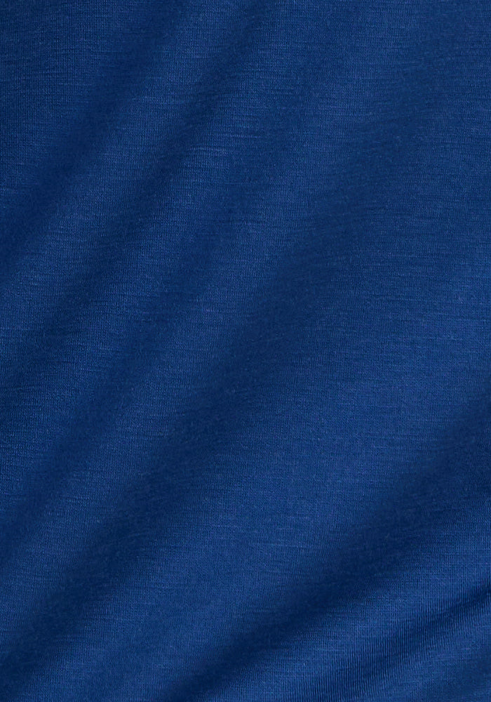 A close-up of Woolx Summit Polo in Estate Blue shows smooth fabric, slight diagonal wrinkles, and moisture management.