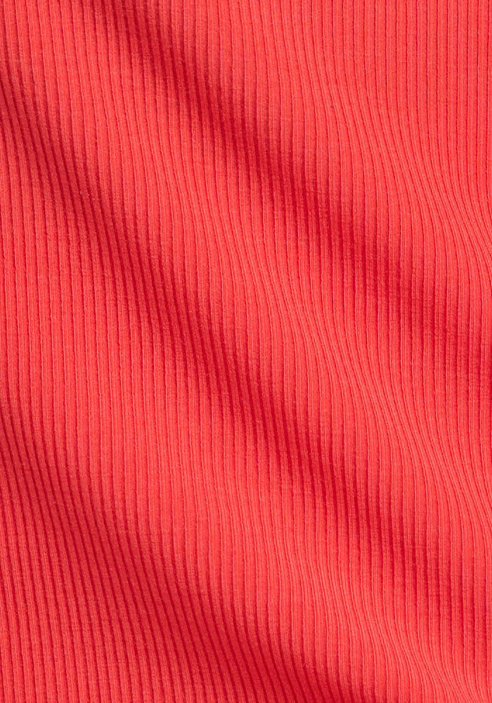 Close-up of Woolx Maisey Ribbed Shorts in Hibiscus, highlighting textured red vertical ribbing and wavy folds.