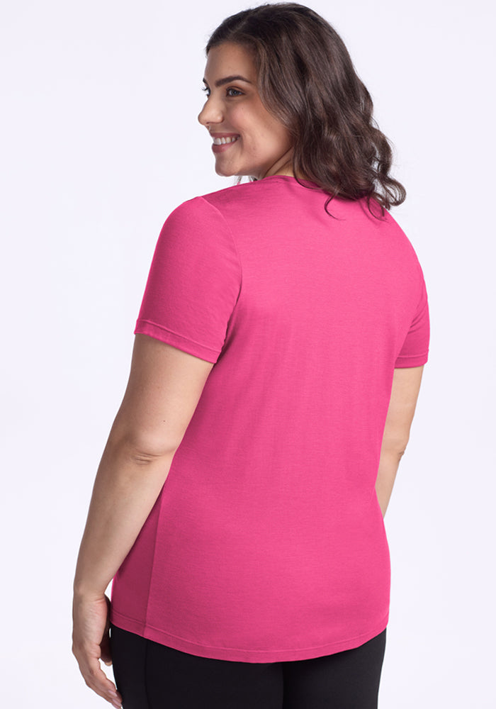 Woman with wavy brown hair wearing the Woolx Junie V Neck in Raspberry Fizz, facing away and smiling.