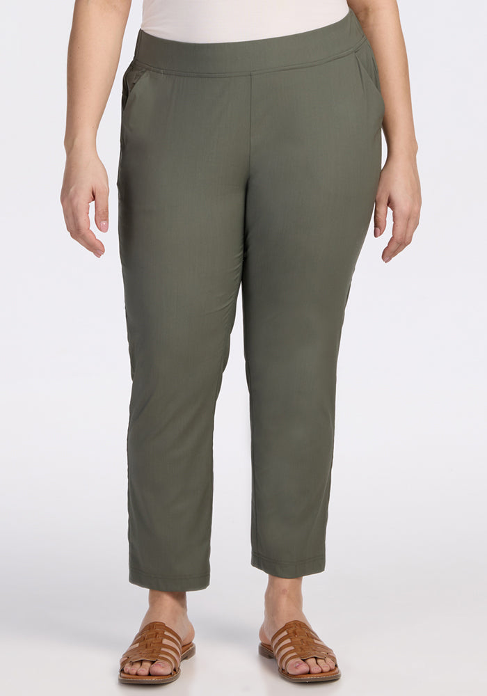 A person stands against a plain white background wearing Woolx Nicole Ankle Pants in Sage Olive and brown sandals, hands relaxed at their sides. 