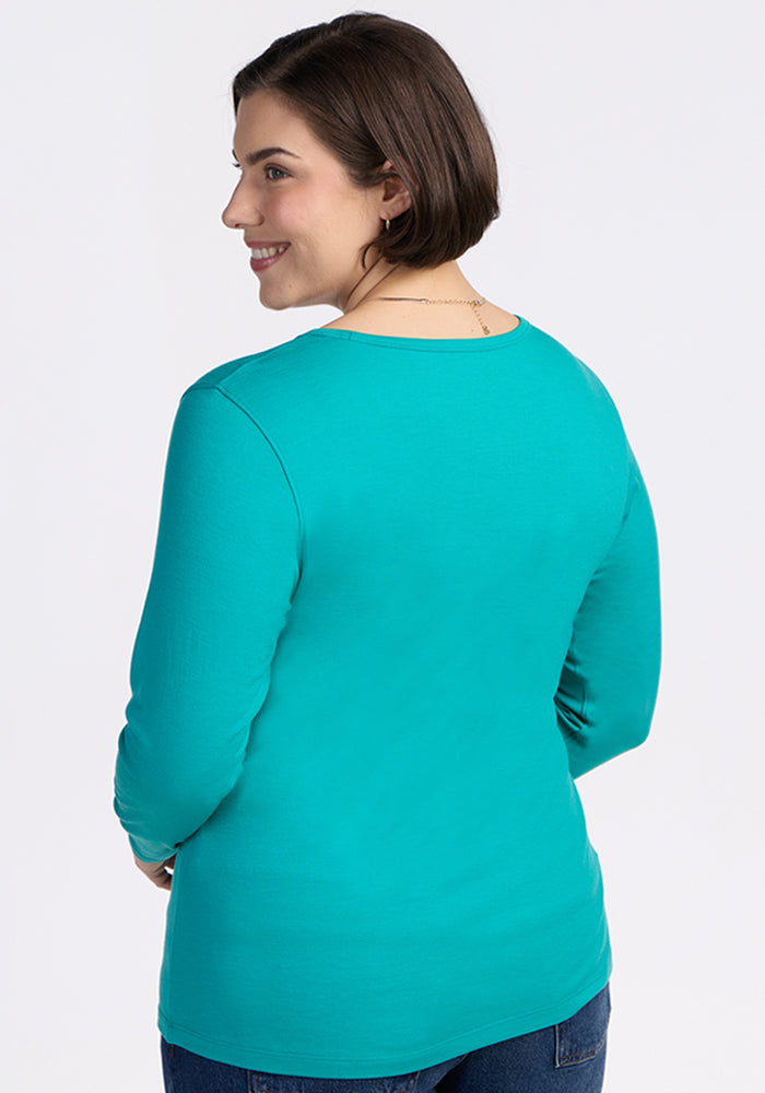 Smiling woman in a Woolx Remi Long Sleeve T-Shirt in Cool Jade, shown from the back looking over her shoulder.