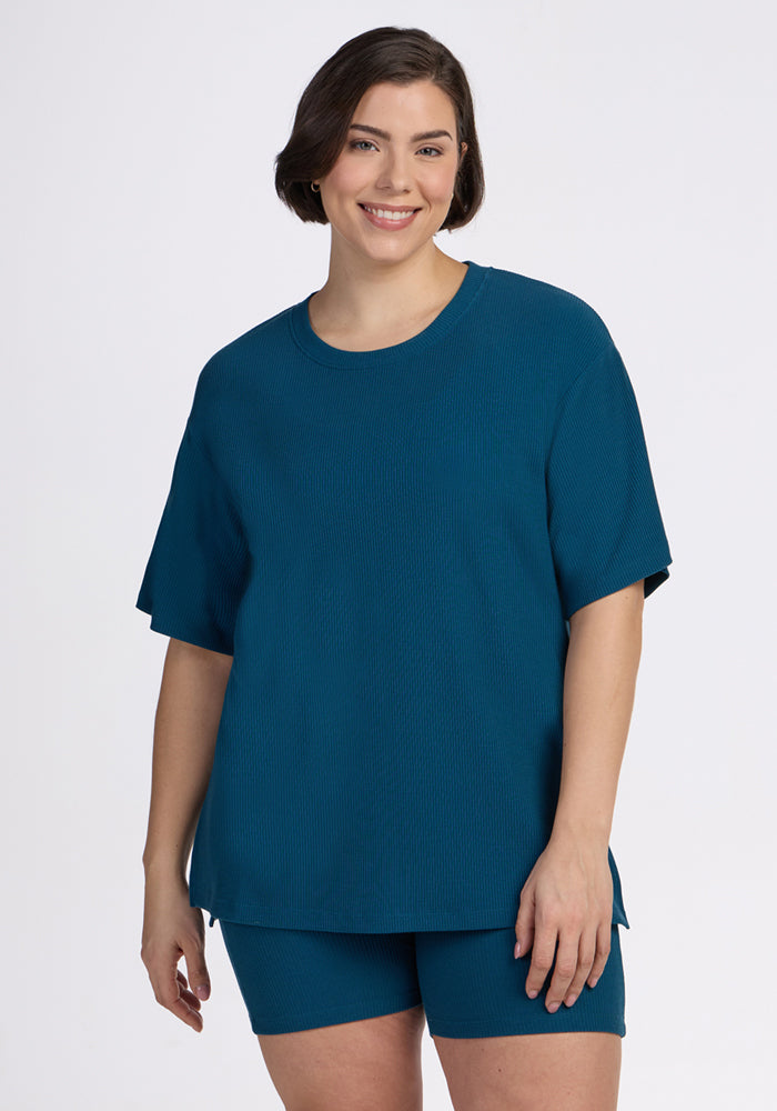 Smiling person in the Woolx Vera Ribbed Tunic in Moroccan Blue, standing against a plain white background.
