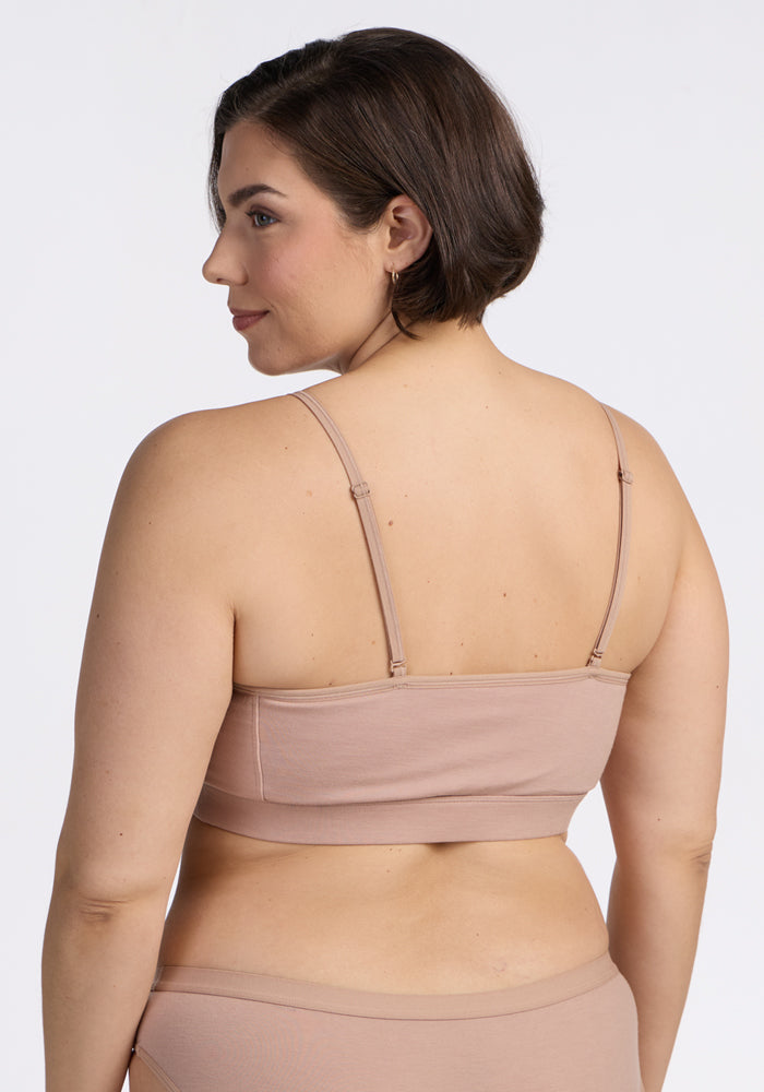 A woman with short brown hair is shown from the back, modeling the Woolx Luna Bralette - Morning Latte and matching underwear against a plain white background, while looking over her left shoulder.