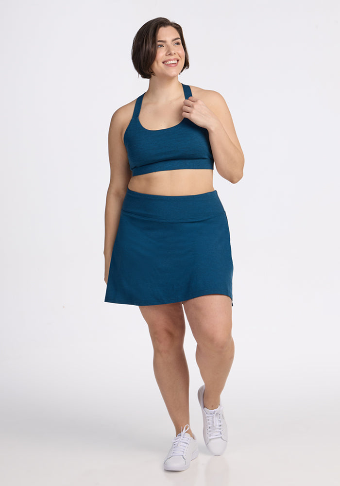 Woman in Woolx Livi Bra • Final Sale - Majolica Blue and white sneakers, standing against a plain white background.