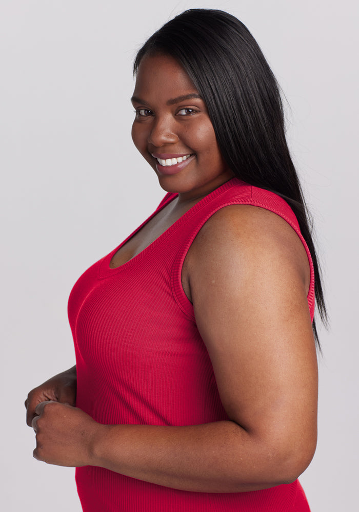 Woman wears the Woolx Sloane Ribbed Tank in Poppy Spark, smiling with long straight hair against a plain light background.
