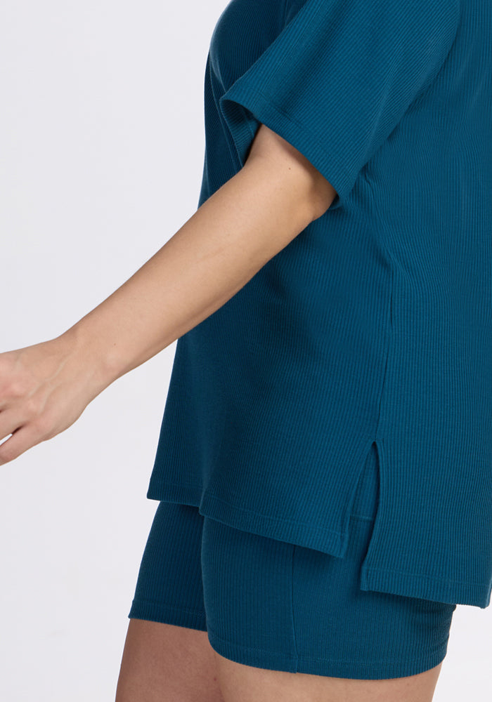Model in Woolx Vera Ribbed Tunic, Moroccan Blue, relaxed fit, shown from the side with matching shorts.
