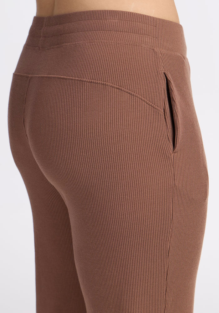 Close-up of a person wearing Woolx Luca Ribbed Pants in Sienna Kiss, showcasing the textured fabric, side pocket, and comfortable fit.