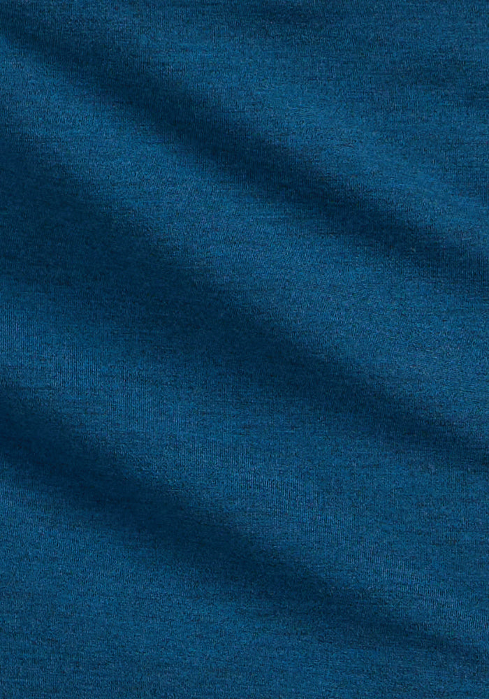 A close-up of the Woolx Ava Tank Top in Majolica Blue shows its smooth, lightweight merino wool fabric with soft texture and diagonal shadows that highlight gentle folds.