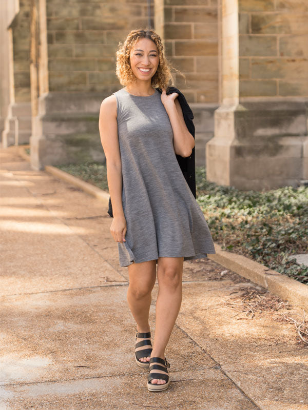 Woman in a gray dress standing outdoors on a stone path with a building in the background
