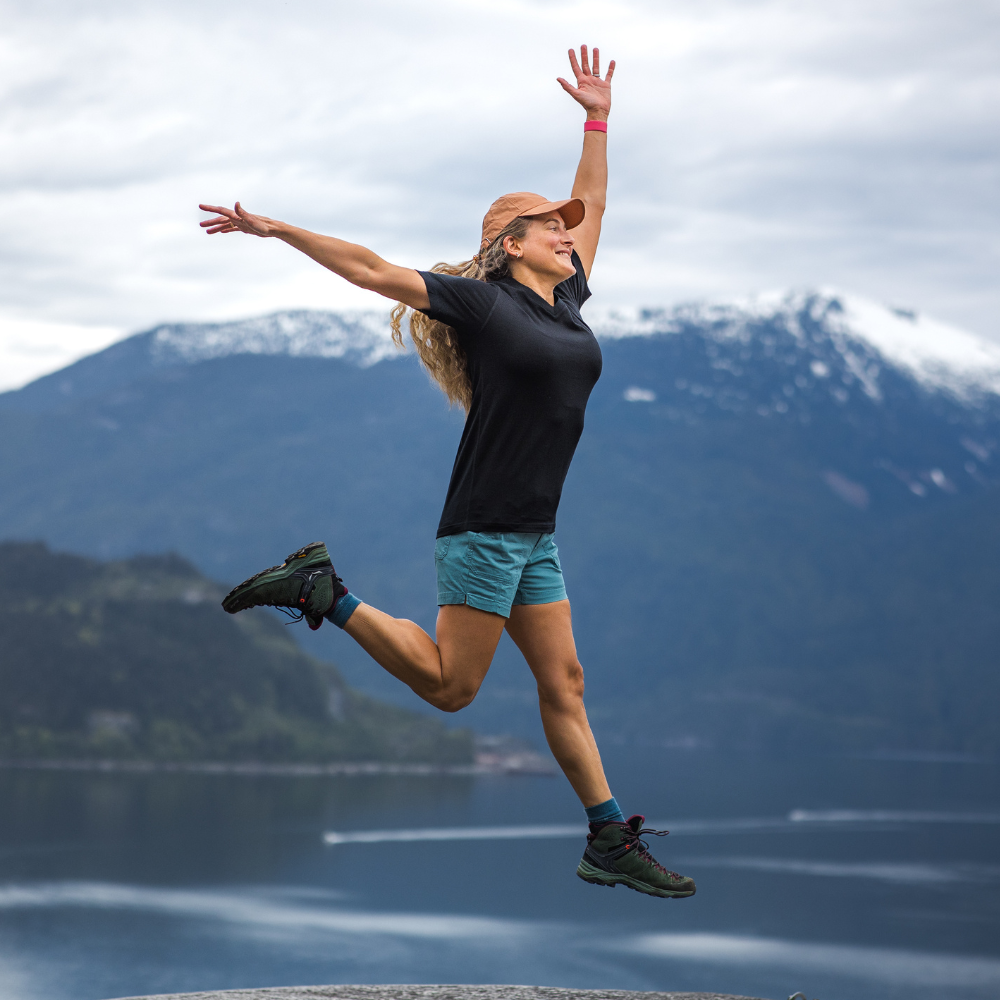 Woman jumping in air wearing black Mia tee