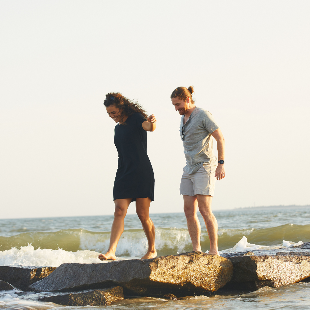 Man and woman standing on rocks at beach