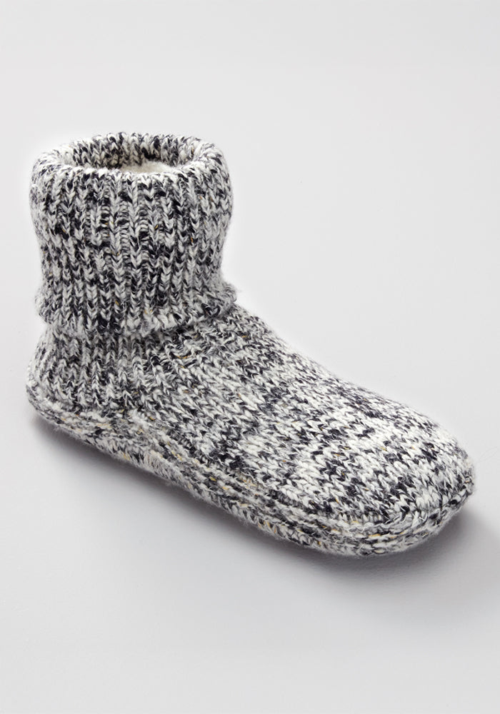 The Woolx Women's Gripper Slipper Booties in Speckled Stone feature a grey and white cozy design with a thick ribbed ankle cuff, shown against a plain light grey background.