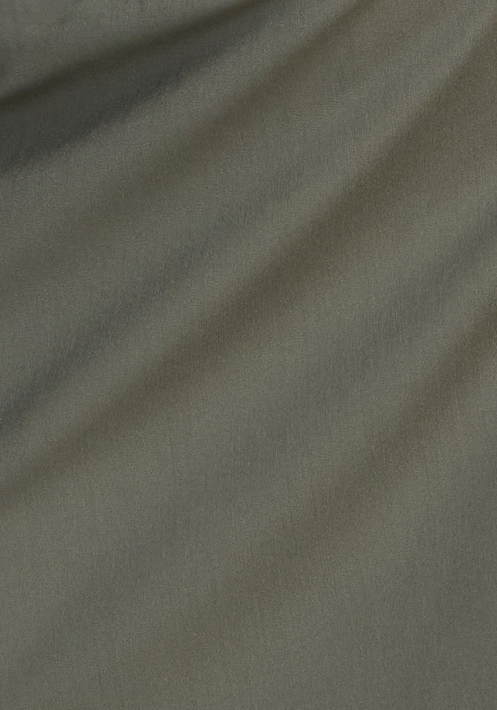 Close-up of the smooth sage olive fabric used for Woolx Palmer Joggers, featuring subtle diagonal folds and soft shadows—ideal for creating lightweight, comfortable travel joggers.