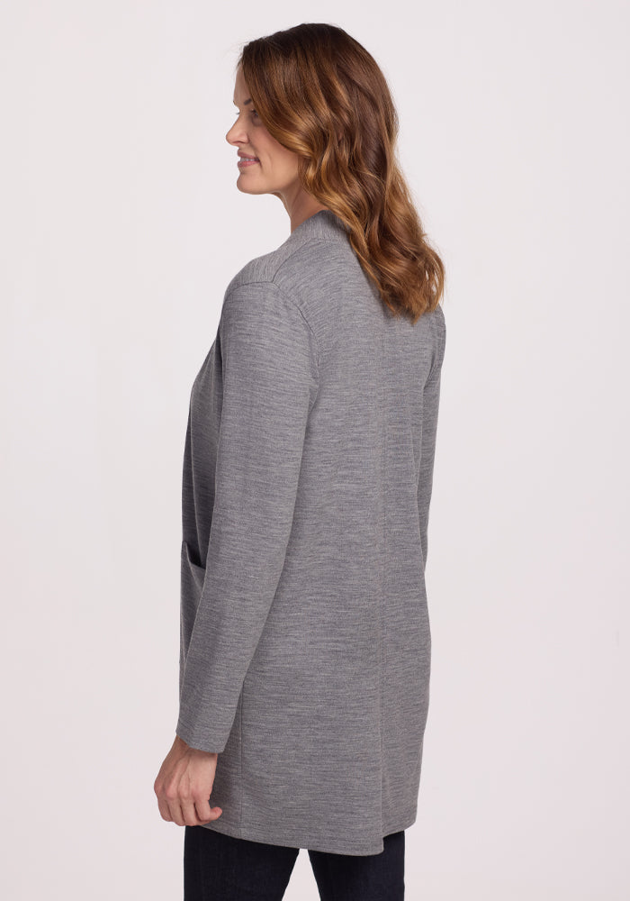 A woman with shoulder-length brown hair wears the Woolx Paisley Cardigan in Graphite Heather, known for its feather-light comfort, along with dark pants. She stands in side profile against a plain white background.