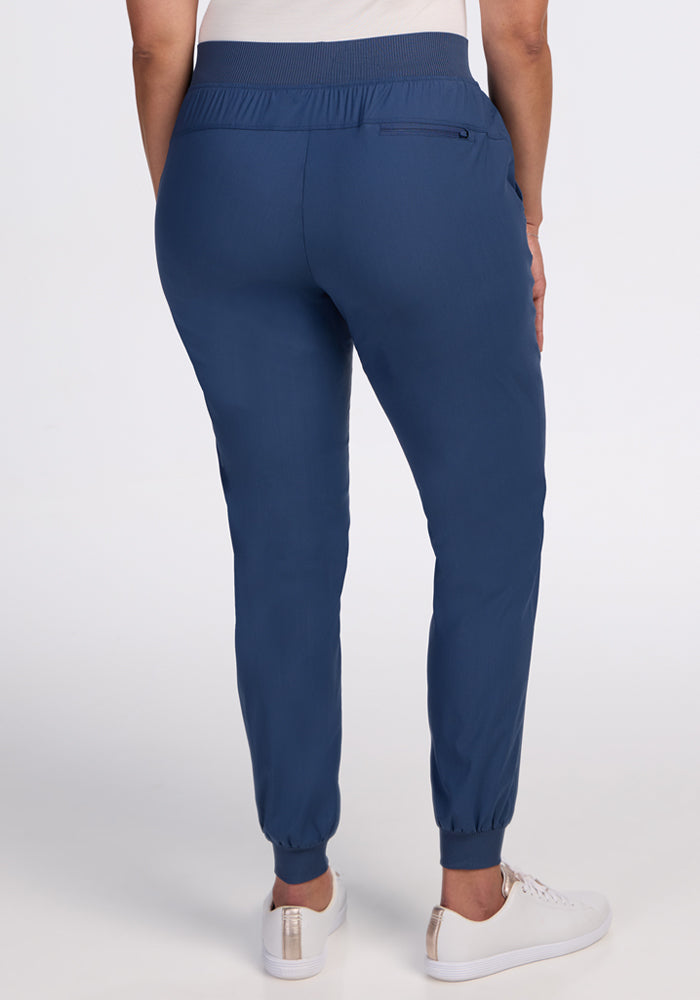A person models the Woolx Palmer Joggers in Vintage Indigo, paired with white sneakers, facing away to display the back view against a plain white background.