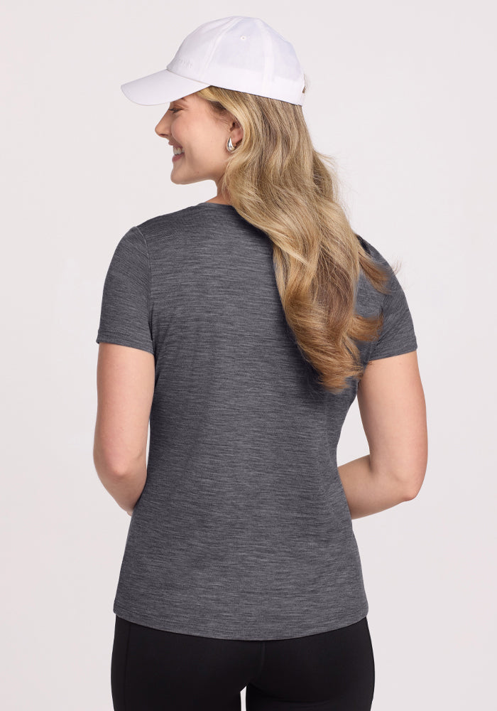 Woman in a Woolx Junie V Neck • Final Sale - Cinder Melange tee and white cap, smiling against a light background.