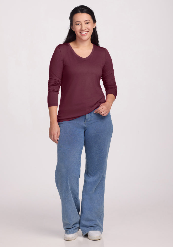 Woman smiling, wearing the Woolx Millie Long Sleeve in Grape Harvest and blue jeans against a light background.