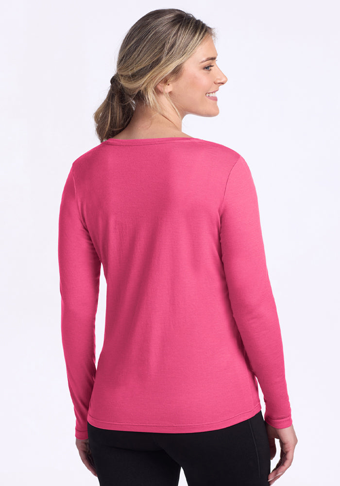 A woman with light hair wears the Woolx Millie Long Sleeve in Raspberry Fizz, shown from the back on a white background.