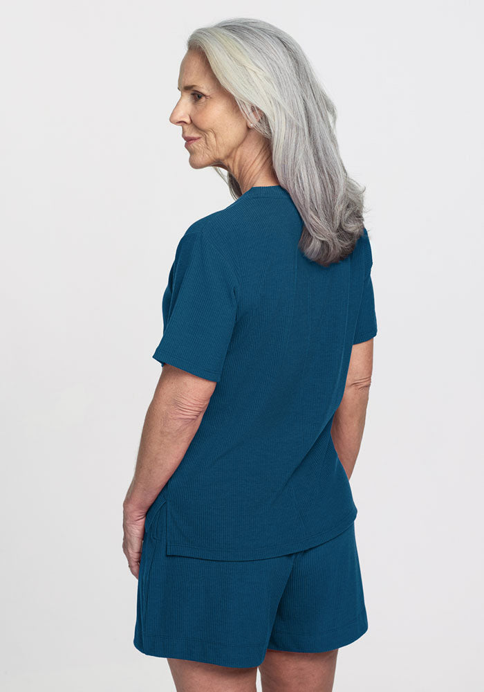 Older woman in Woolx Delia Ribbed Short Sleeve and shorts, Moroccan Blue, standing sideways. Final Sale.