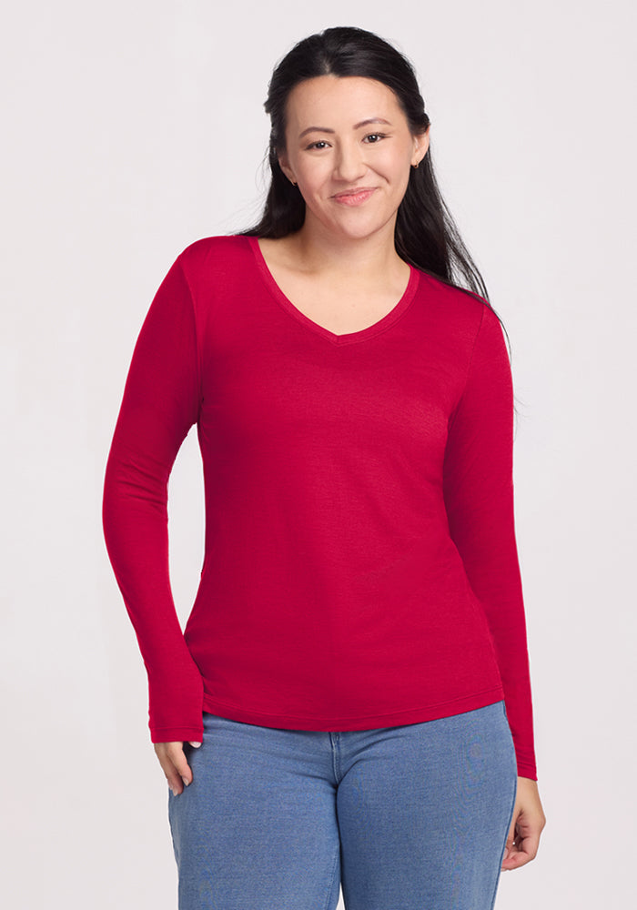 Woman in a Woolx Millie Long Sleeve (Poppy Spark) and blue jeans, smiling against a light background.