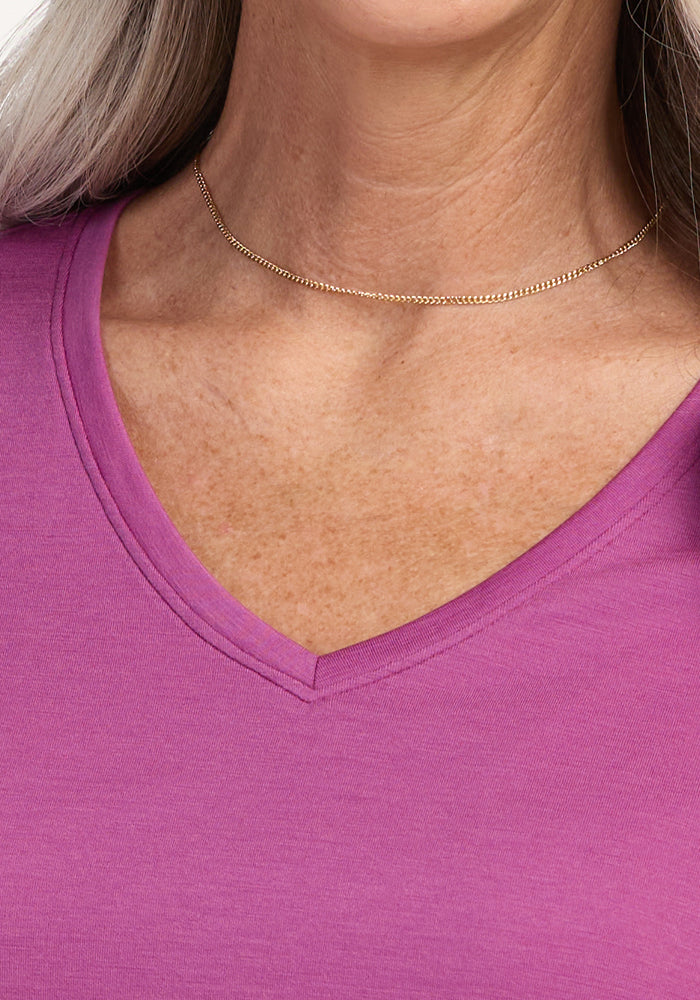 A woman wears a thin gold necklace and the Woolx Junie V Neck in Purple Wine, shown from shoulders to chest.