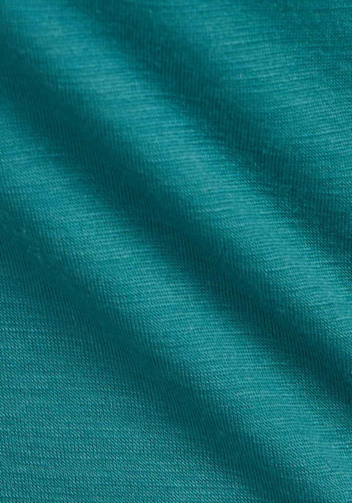 Close-up of Woolx Junie V Neck in Surfside: teal, moisture-wicking fabric with textured, soft diagonal folds.