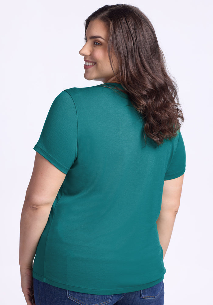 Smiling woman with wavy brown hair wears the Woolx Liza Crew Neck Tee in Surfside, looking over her shoulder.