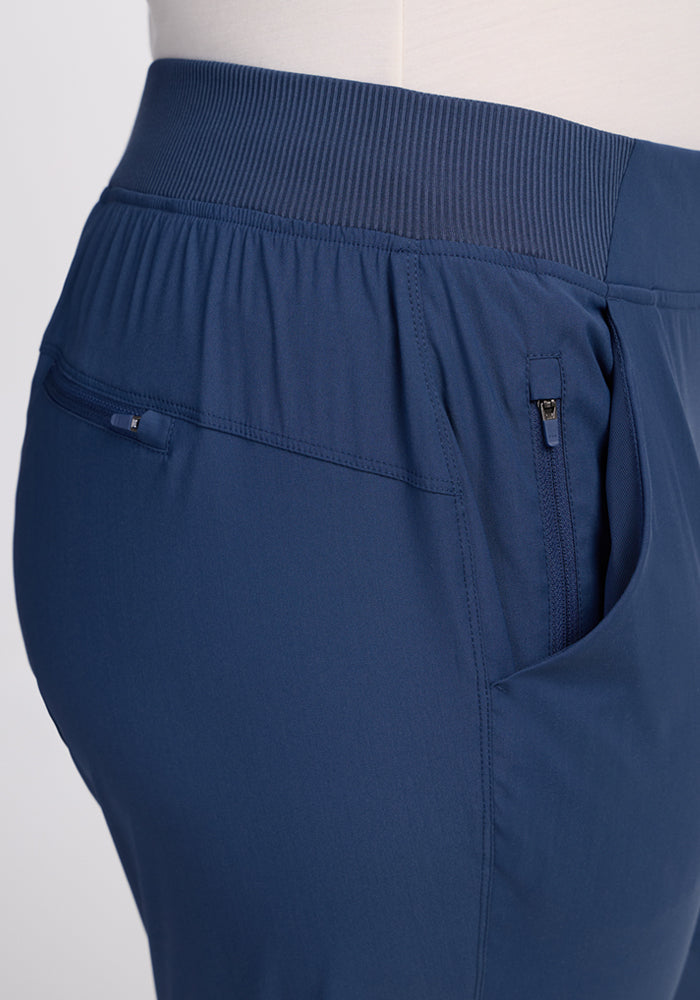 Close-up of a person wearing Woolx Palmer Joggers in Vintage Indigo, featuring a wide elastic waistband, zippered side pocket, and small back zipper pocket. Hip to mid-thigh view. Perfect travel joggers combining comfort and style.