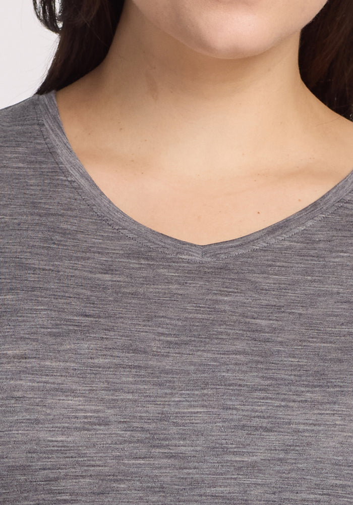 Partial view of a person wearing the Woolx Elena 3/4 Sleeve V Neck in Graphite Heather, highlighting its relaxed neckline and upper chest. The Merino wool's smooth texture adds elegance, with no other features visible.