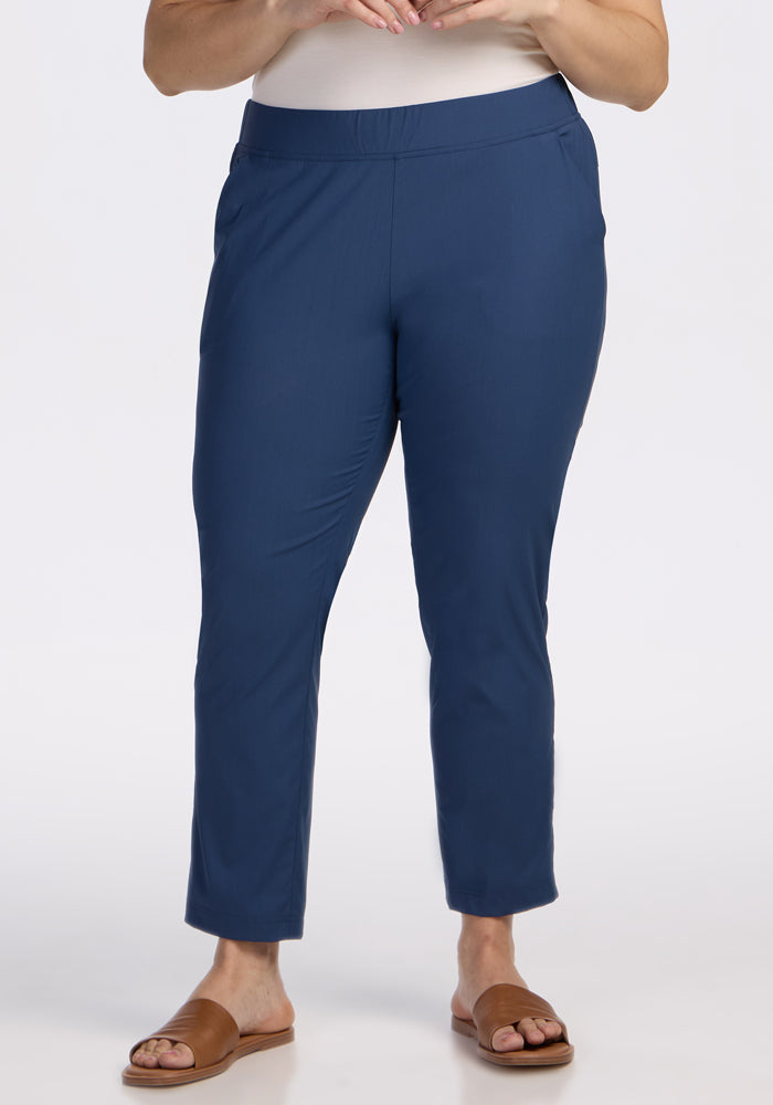 A person models the Woolx Nicole Ankle Pants in Vintage Indigo with brown slide sandals against a white background, showing only the lower half of their body. 