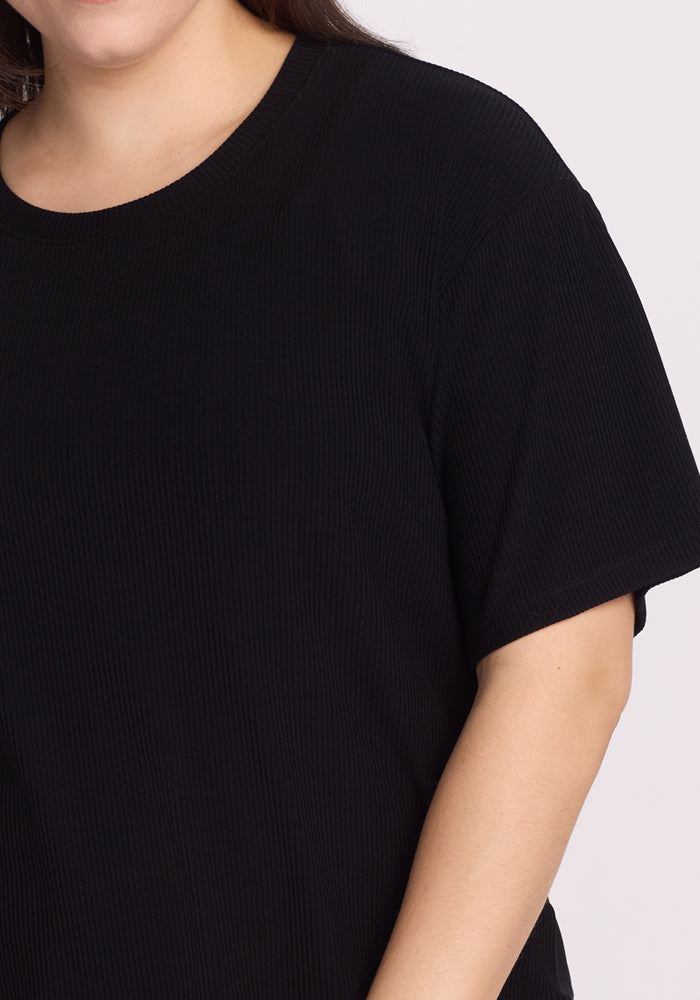 A person wearing the Woolx Vera Ribbed Tunic in black, a relaxed-fit, short-sleeve T-shirt, is shown from shoulders to midsection against a neutral background.