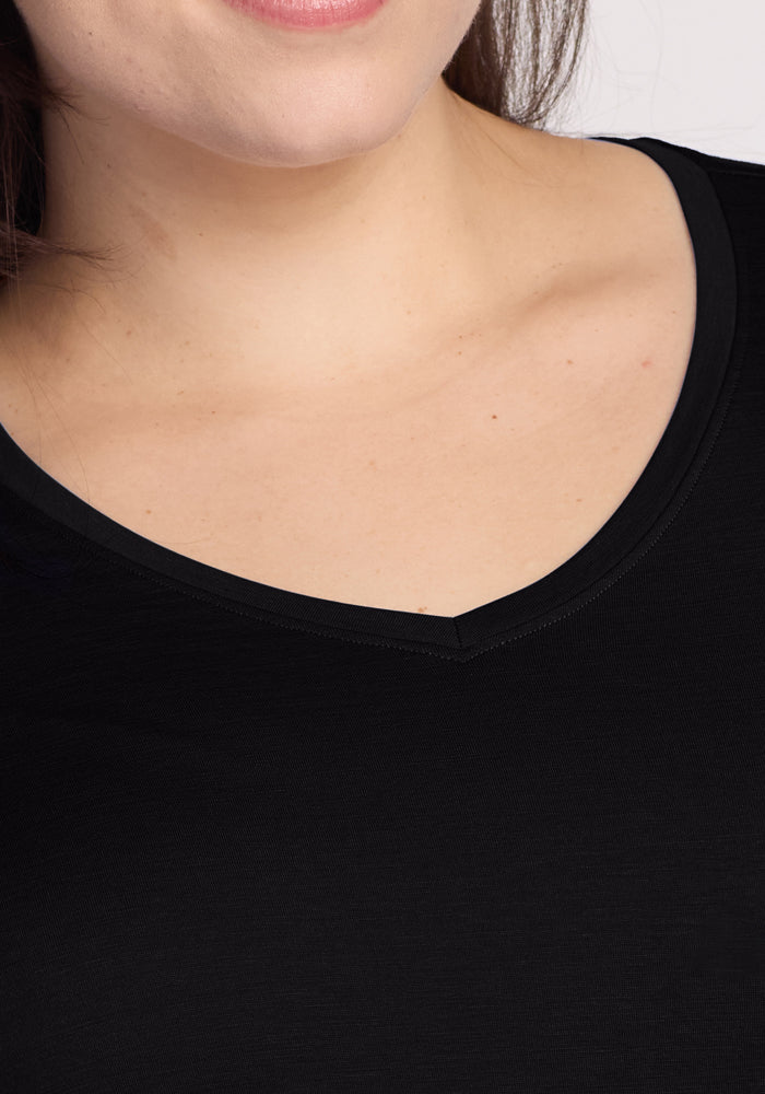 Close-up of someone in a Woolx Millie Long Sleeve - Black, showing only the V-neckline and upper chest, with a glimpse of their hair. The shirt is made from moisture-wicking material.