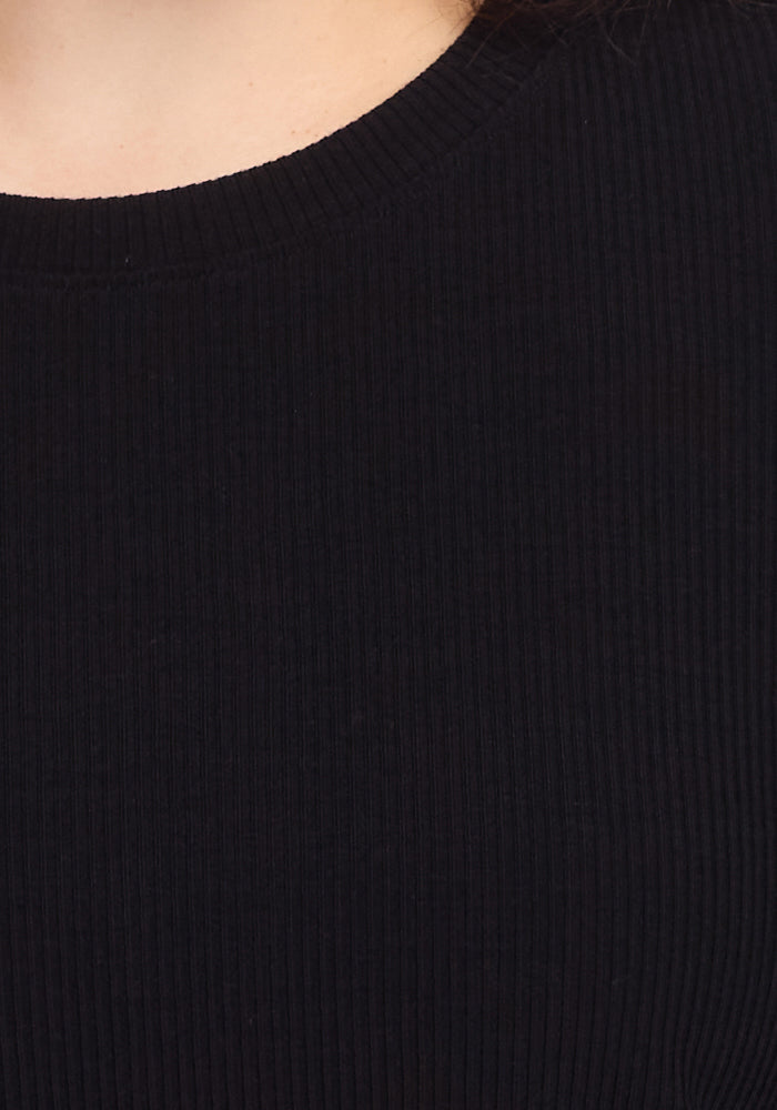 A close-up of a person wearing the Woolx Vera Ribbed Tunic in black, featuring a crew-neck design made from Merino wool, with their neck and upper chest partially visible.